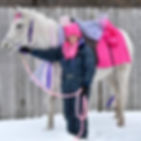 Girl wearing bunny ears standing next to white horse wearing bunny ears