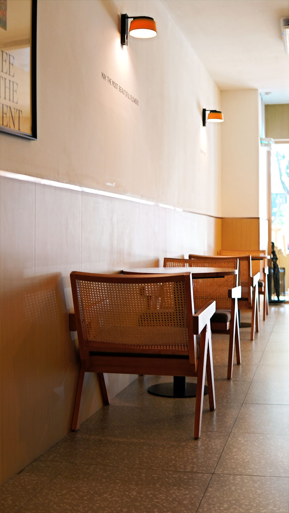 rattan chairs and wooden table placed by the wall with lamp and paintings hung on the wall