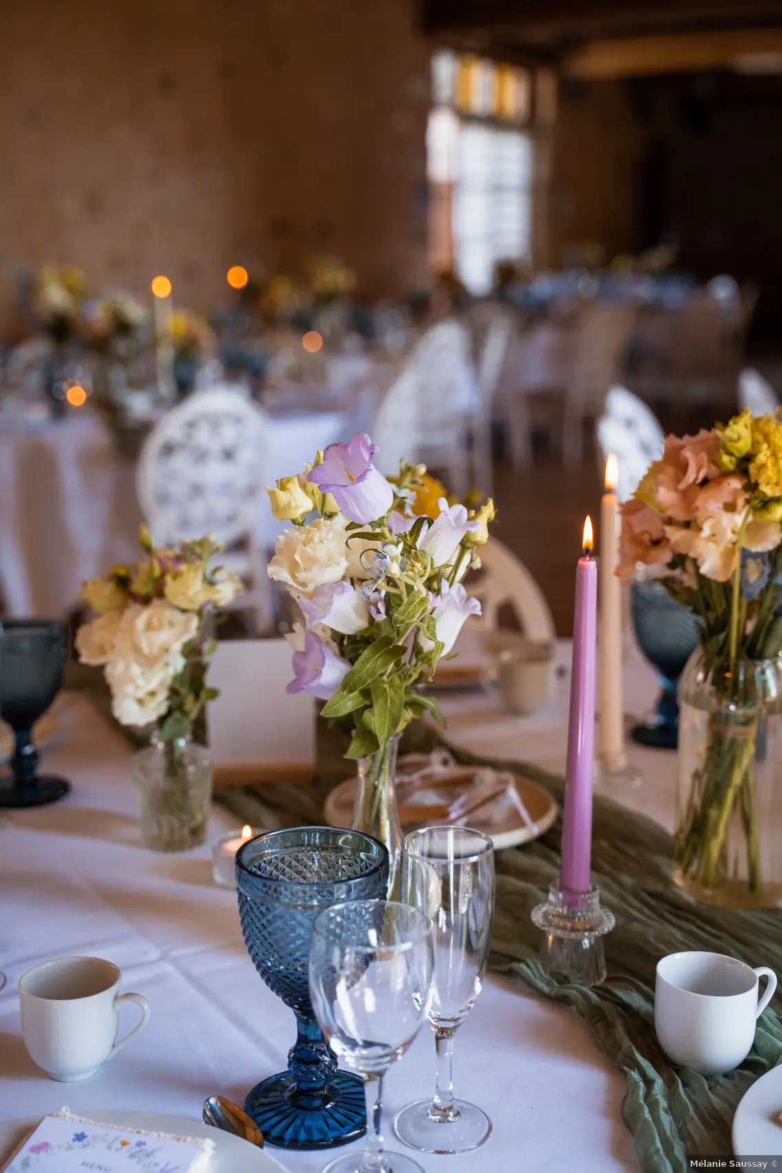 décoration d'une table de mariage couleur pastel avec des bougies hautes, des verres strié bleu et des petites compositions