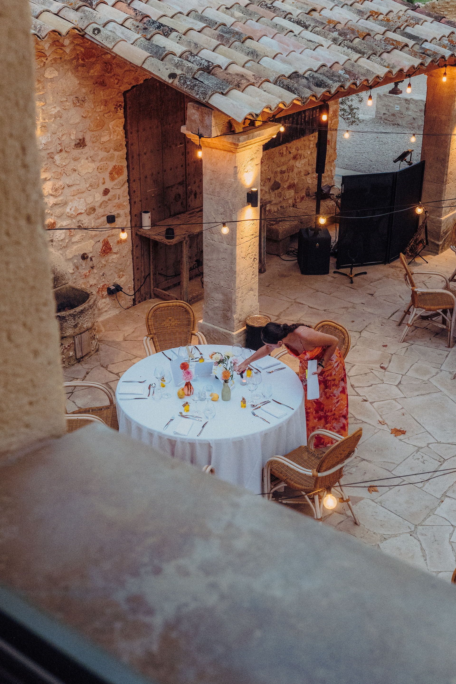 Une wedding planner qui installe les derniers détails décoration de la table d'un mariage en extérieur, elle est concentrée