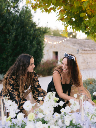 Deux wedding planner qui installment la décoration d'une table de mariage et qui rigolent