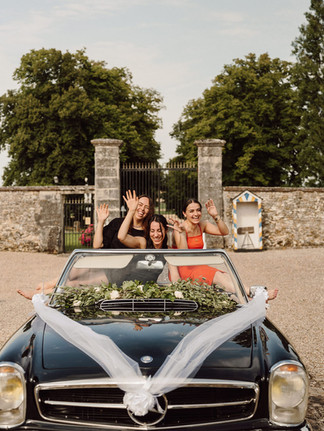 3 wedding planner en shooting dans une voiture à un mariage, dans une voiture ancienne, elles rigolent toutes les trois, la voiture est décoré
