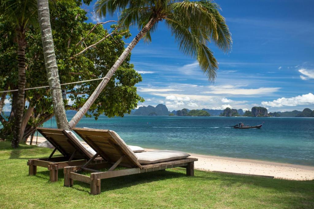 plage privée à Koh Yao Noi avec deux transats face à la mer bleu et des montagnes en fond