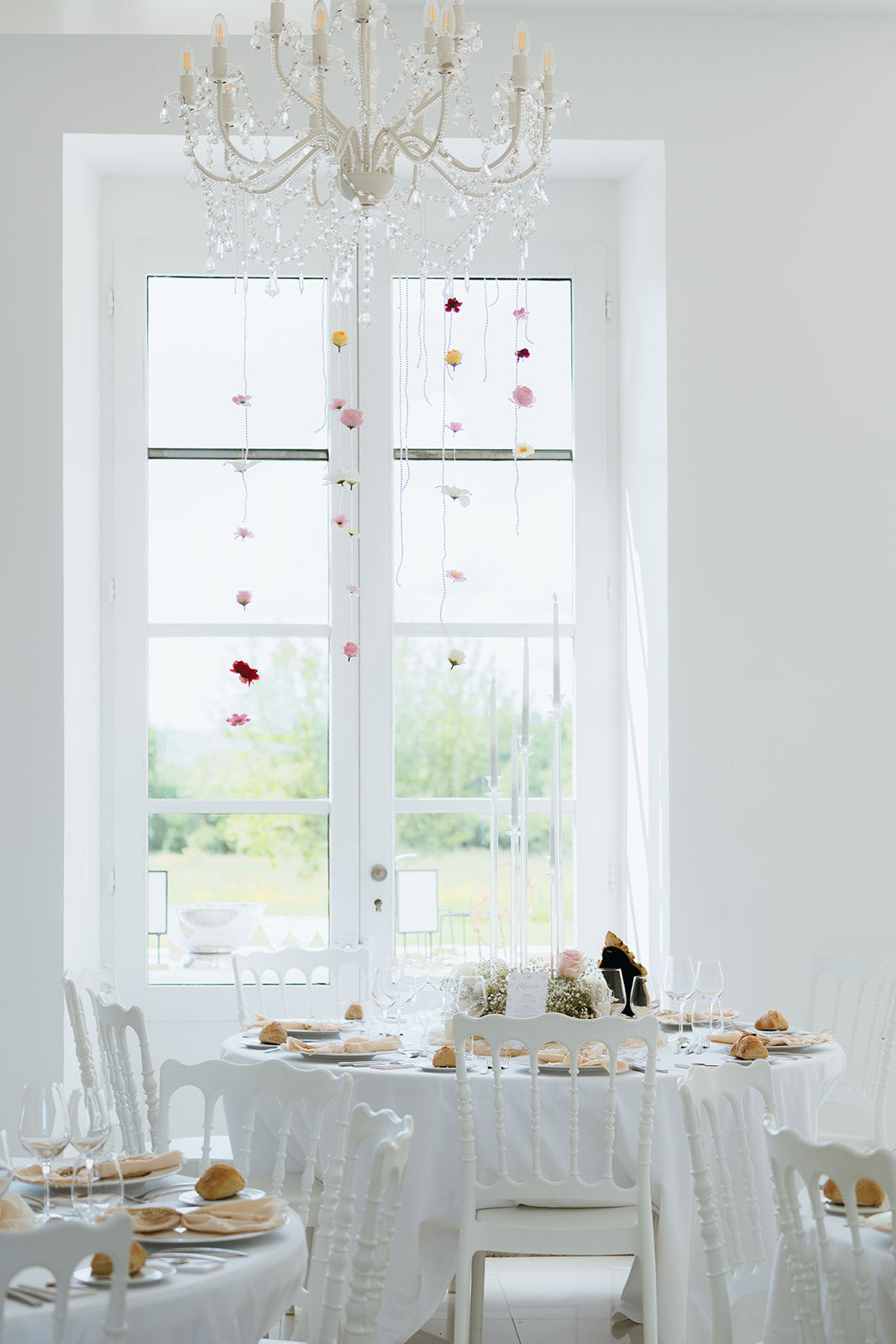 Décoration d'un lustre avec des guirlandes de fausses fleurs et des guirlandes de perles, avec une table de mariage juste en dessous