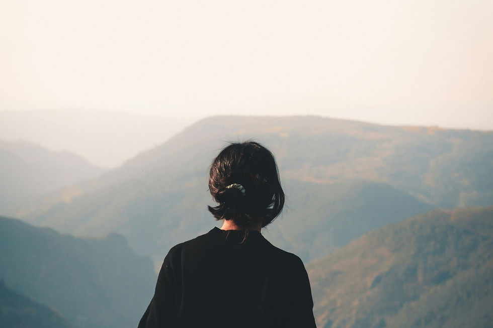 A woman standing alone overlooking misty mountains at dawn, representing the moment women with hormonal symptoms over 40 finally find someone who can explain what their body has been telling them.
