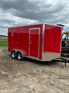 7x16 enclosed cargo trailer featuring a gloss red exterior, blackout trim, tandem axles, rear ramp door, and durable tubular frame construction. In stock now at Team Trailers.