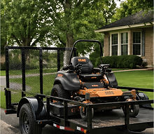 Utility trailer loaded with lawn mower and landscaping equipment
