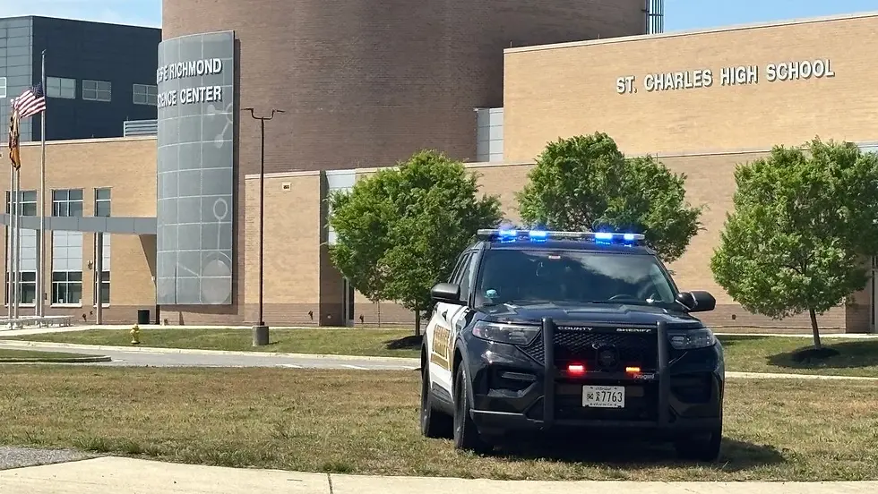 Eye-level view of St. Charles High School entrance with police vehicles parked outside