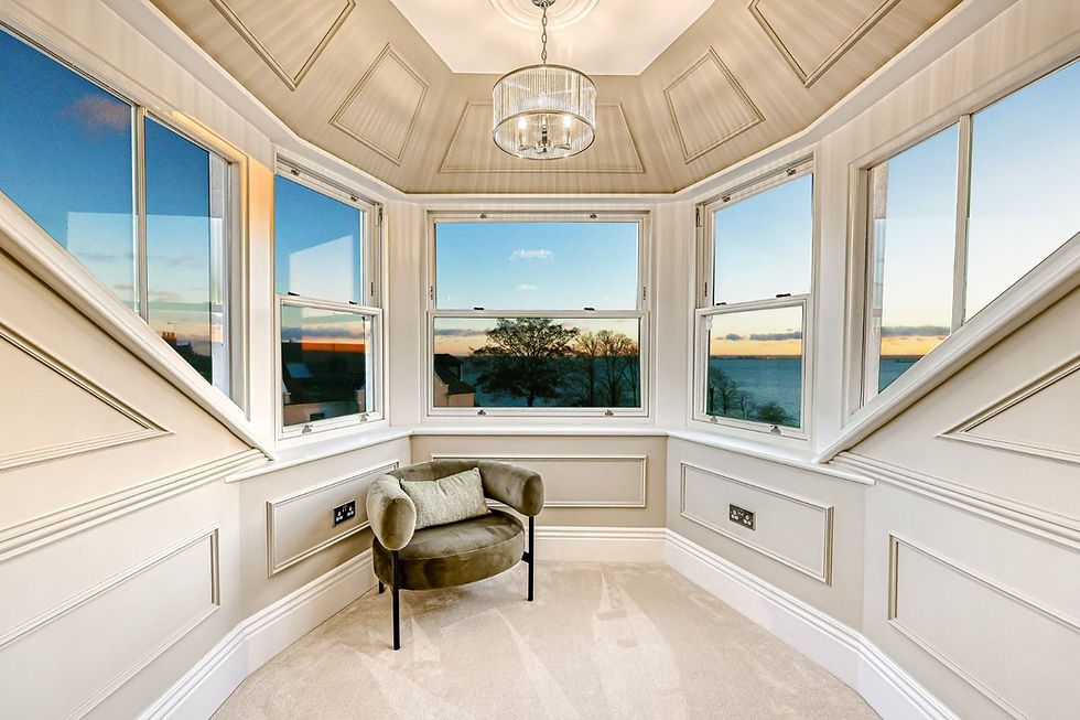 Bespoke timber sash bay window with angled casement side lights and slimline double glazing, overlooking coastal view at sunset