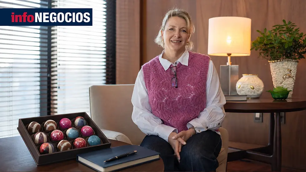 Mónica Sniadower, socia directora de Quiero Chocolate, sonriendo junto a una caja de bombones artesanales, durante la entrevista con InfoNegocios Uruguay