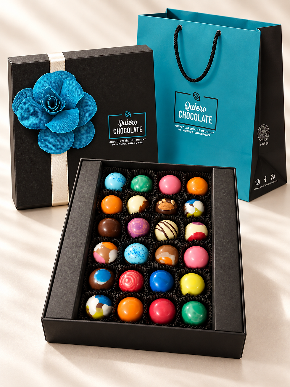 Miniatura: Caja abierta con 24 bombones artesanales de chocolate belga, Colección Florencia con rosa de tela azul y bolsa de regalo turq