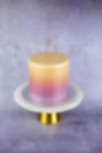 A vegan cake in a very special ombré, namely a color gradient reminiscent of a sunset from purple to orange.