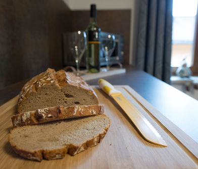 Detailaufnahme der Küchentheke im Appartement Julia mit frisch aufgeschnittenem Brot auf einem Holzbrett