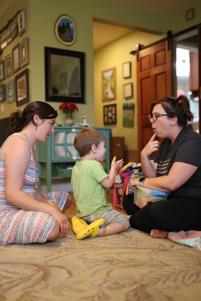 Speech therapist coaching parent during speech therapy session with toddler.