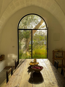 dining table set beneath arched window with garden view