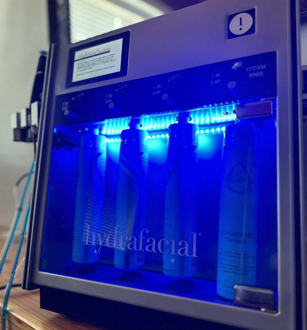 Professional HydraFacial machine with glowing blue LED lights and treatment serums at Revive Spa & Lash Lounge.