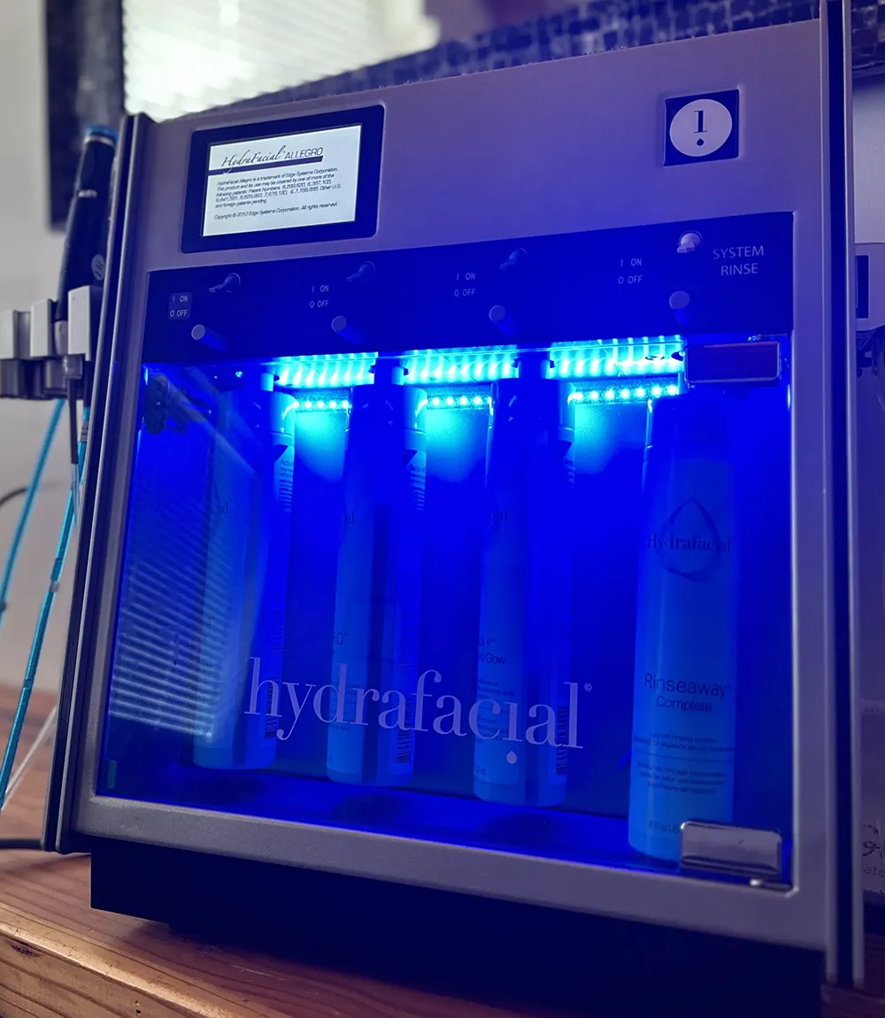 HydraFacial machine displaying treatment serums and blue LED lights, ready for a skincare treatment.