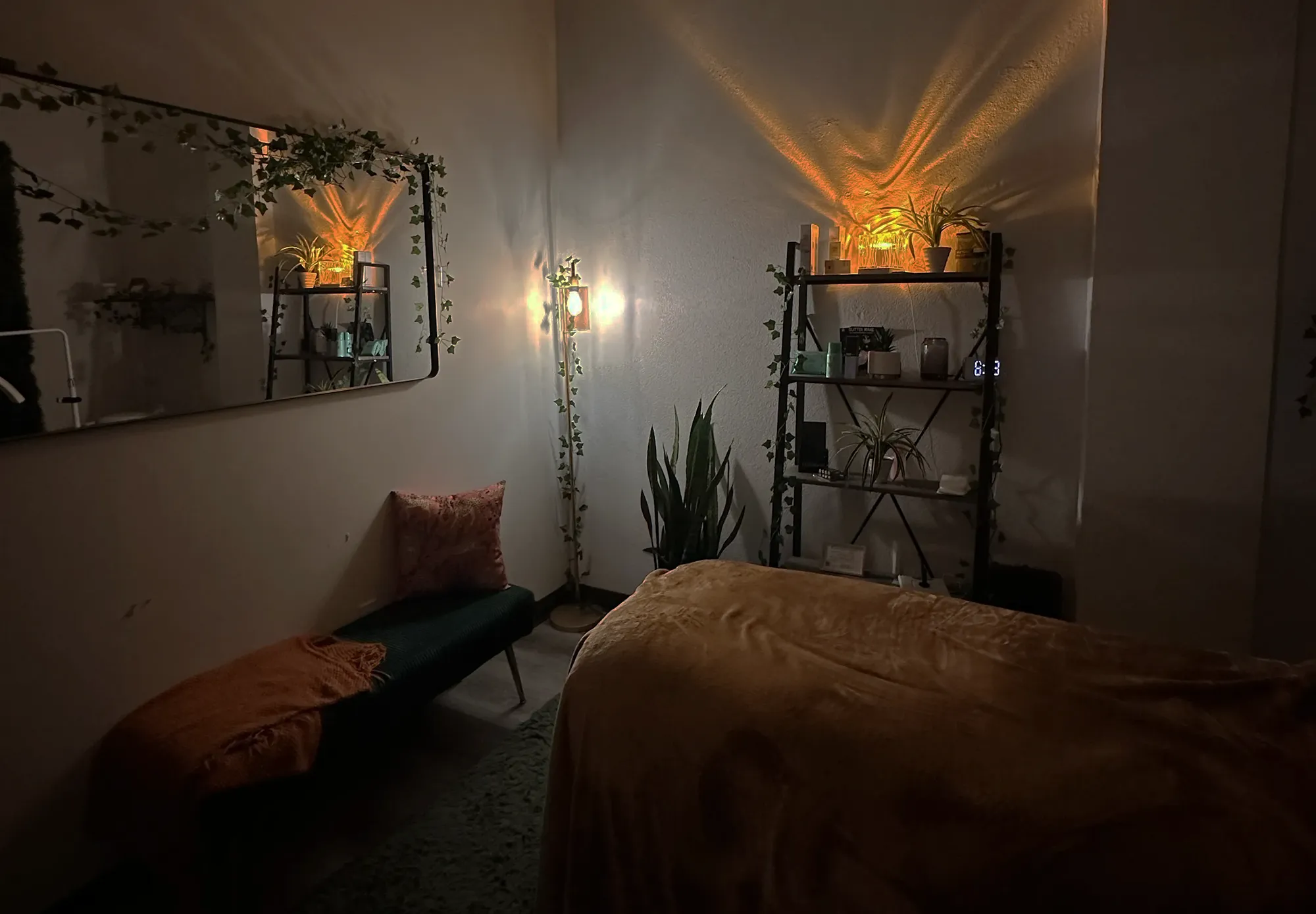 Tranquil treatment room at Revive Spa & Lash Lounge with soft lighting, greenery, and a cozy massage table for facials and spa services.