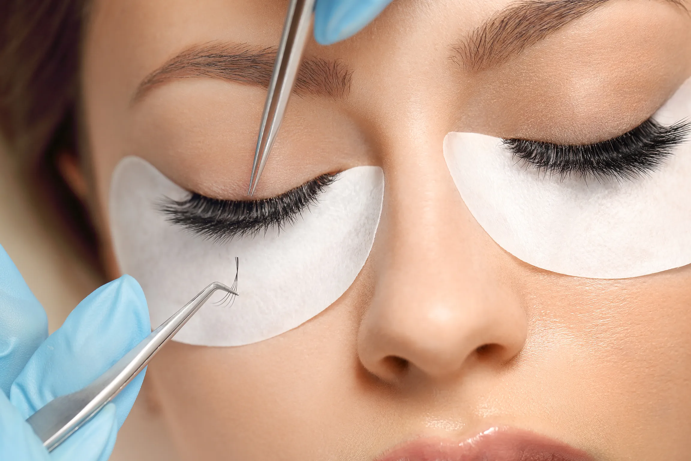 Close-up of lash extension application using tweezers at Revive Spa in Southern Pines, demonstrating expert precision and care
