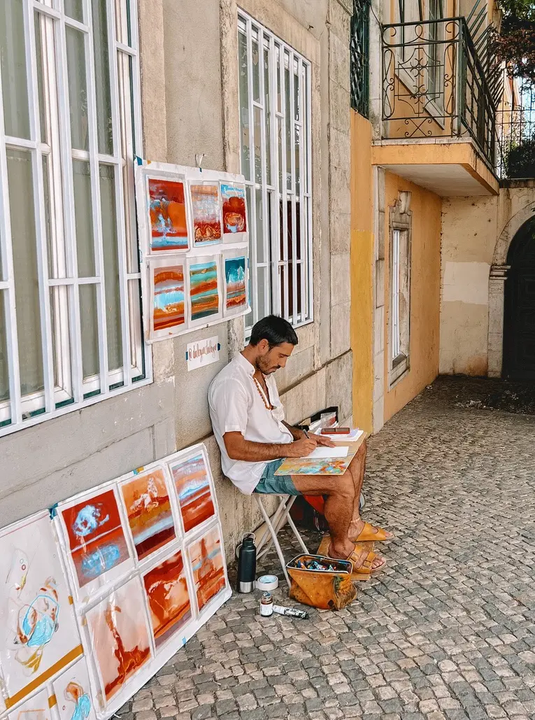 man sitting on chair painting in lisbon