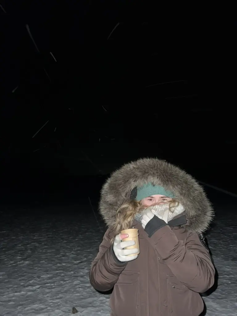 girl in big snow jumper holding hot chocolate