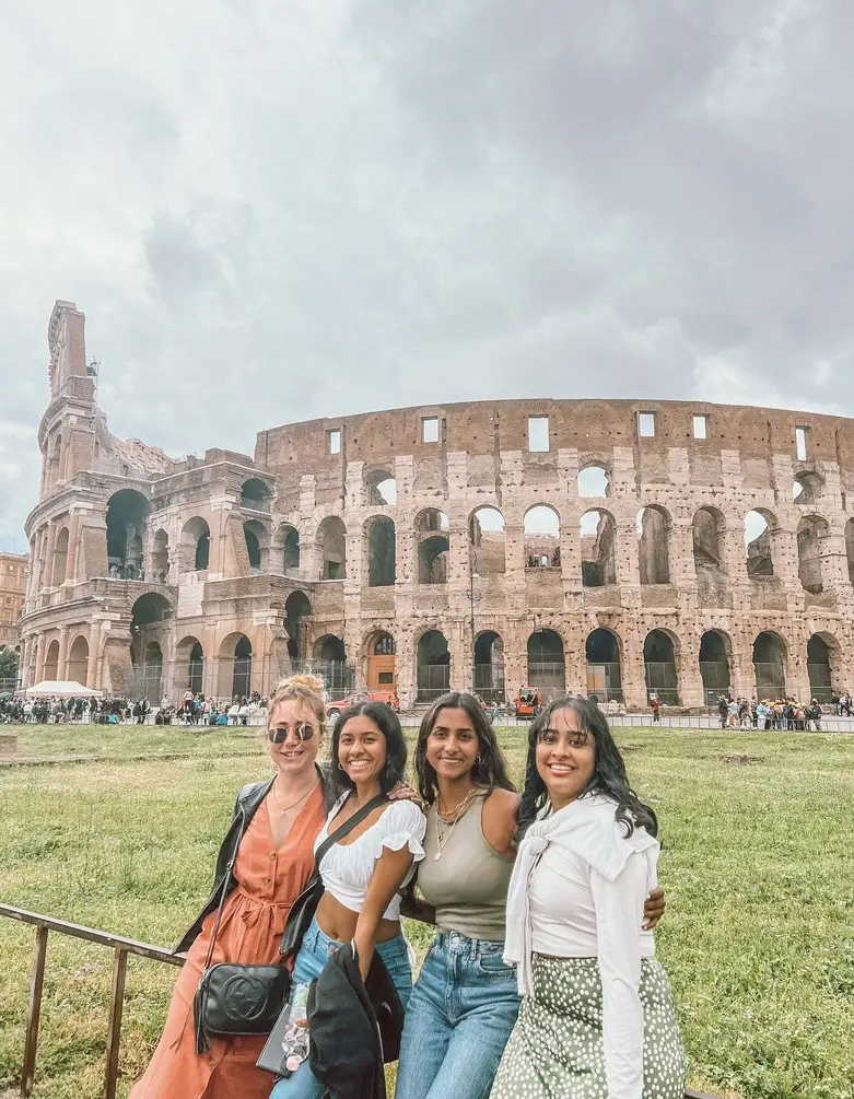 four girls smiling outside Colosseum in rome 