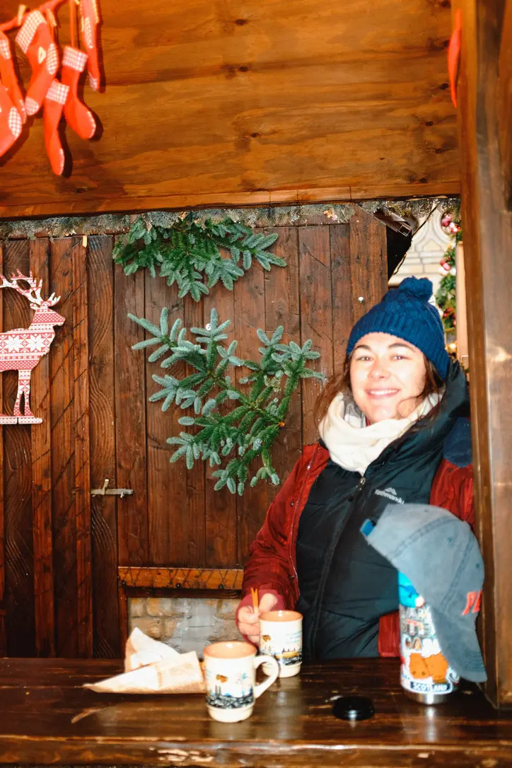 Girl smiling at Germany Christmas Markets with mulled wine on table