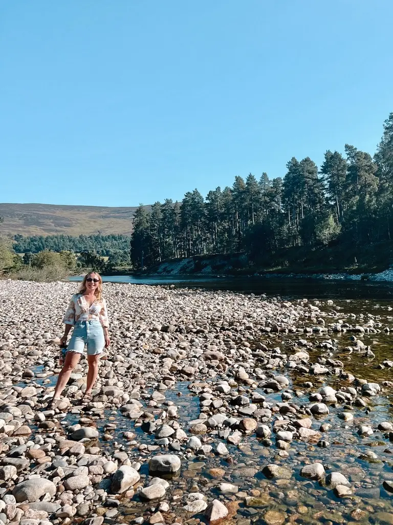 girl smiling at river dee with mountains in background in ballater scotland
