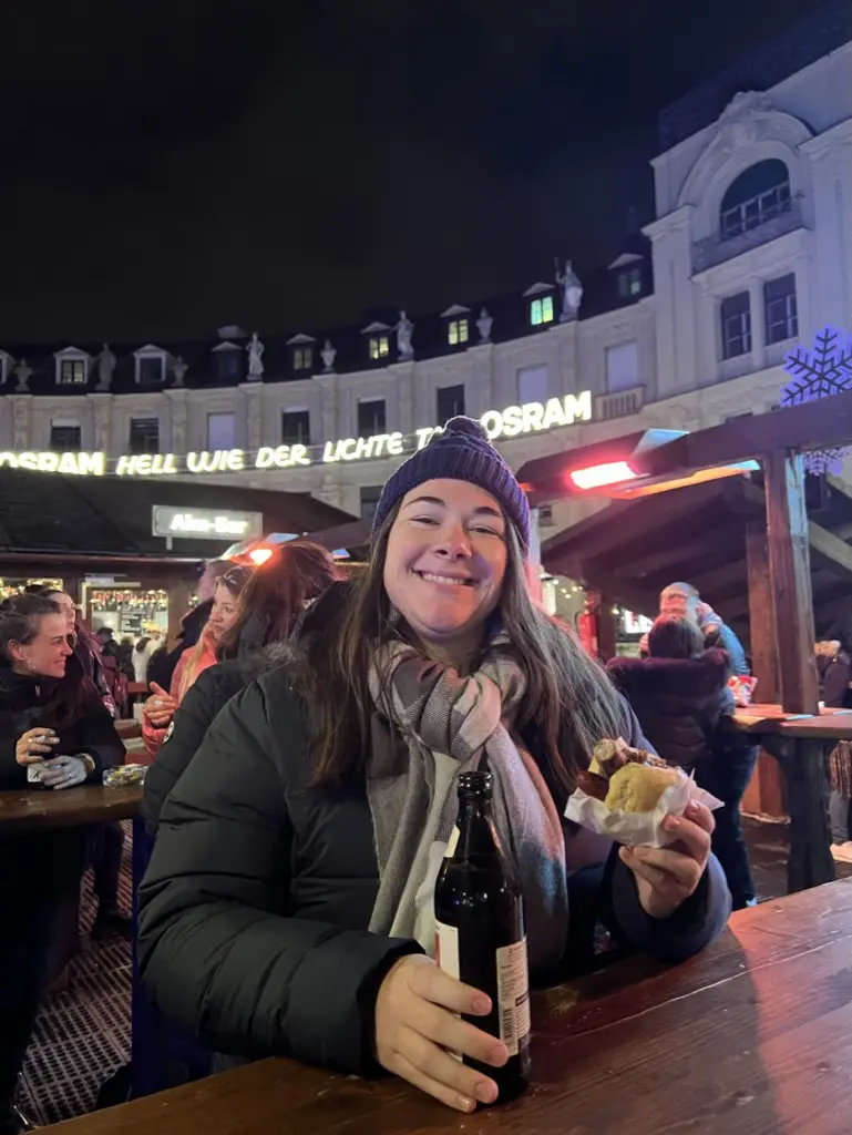 girl smiling drinking beer and sausage roll with beanie on
