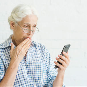 older woman looking worried at a suspicious message on her smartphone
