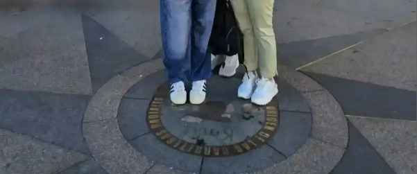 Feet standing on the symbolic Kilometer Zero plaque in Puerta del Sol, Madrid.