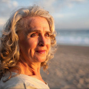 Thoughtful mature woman looking at the sea at sunset, reflecting on life and aging