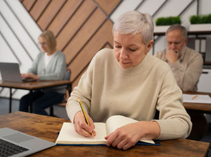 Mujer mayor escribiendo en un cuaderno mientras aprende para mantener la memoria activa después de los 50.