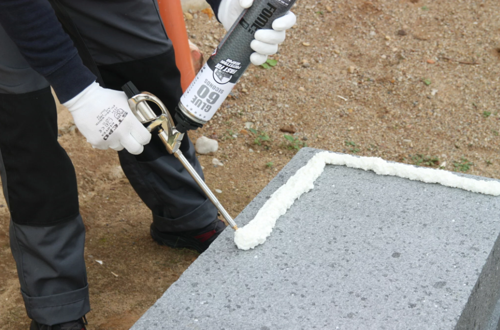 Eye-level view of foam adhesive being applied in beads to an insulation board.