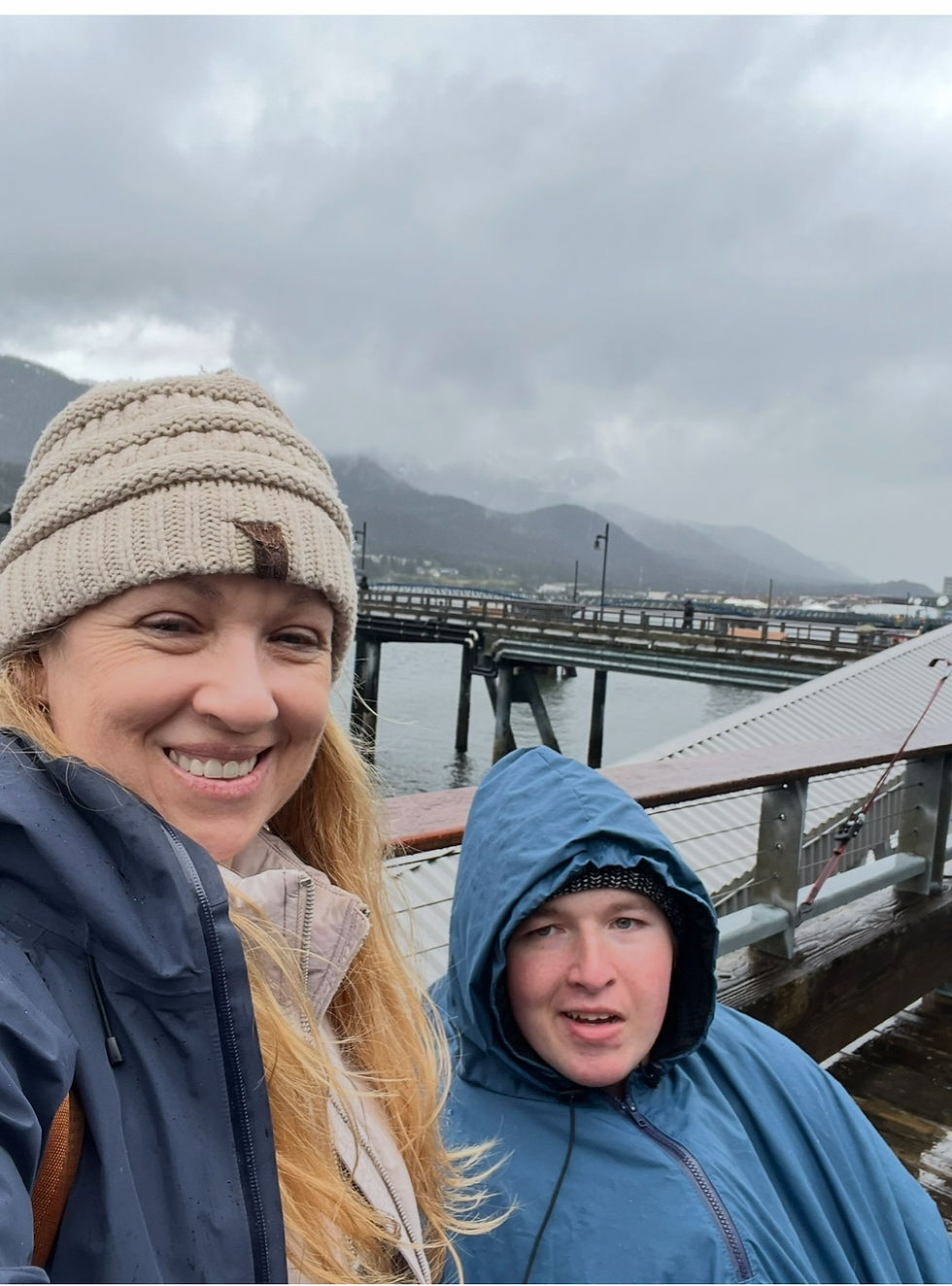 Michele and Jonny bundled in jackets on a rainy dock, smiling as they explore despite the cold weather.