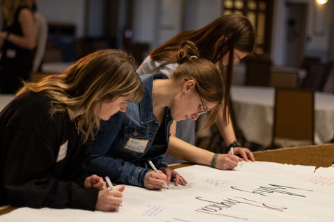 A group of UW Madison graduate students take a moment to sign the UW Madison Physical Therapy Club banner while being photographed by Emanuel Noel Photography in Madison, WI. 