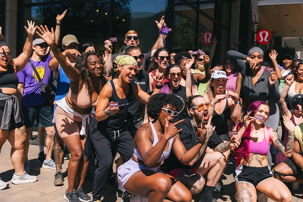 Image of diverse group of men and women after a group fitness class cheering in front of a lululemon