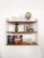 Etagère string vintage des années 60 avec des biblo sur un fond blanc