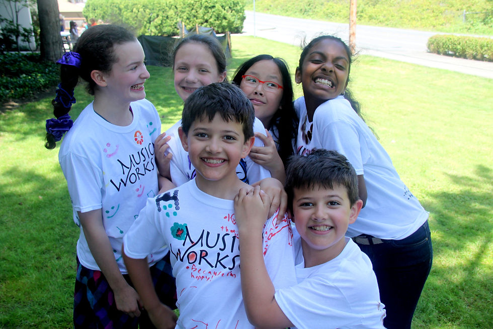 Six children smiling, some wearing 'Music Works' t-shirts