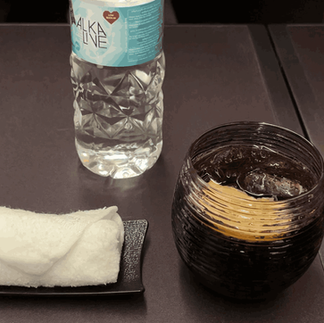 Getränk und ein Erfrischungstuch in der Qatar Airways Business Class in der Qsuite in der Boeing 777-300ER