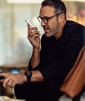 Man speaking into his phone while seated indoors