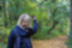 A blonde girl taking a selfie photo in the woods