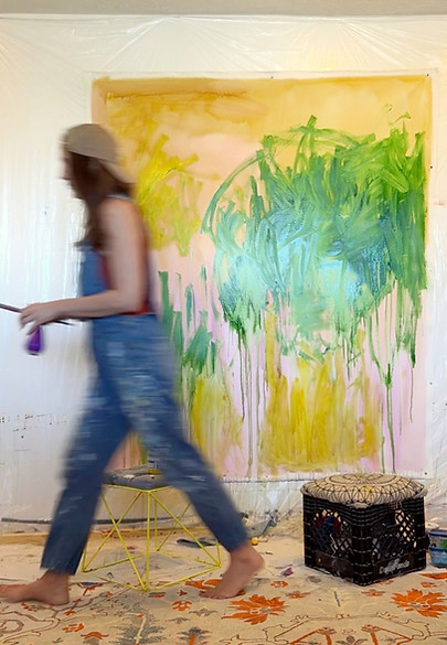 Artist working in her studio on large abstract paitning