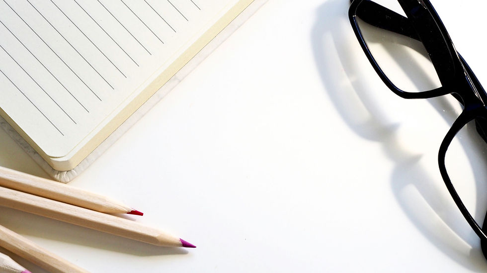 Journal, glasses, and colored pencils on a white desk
