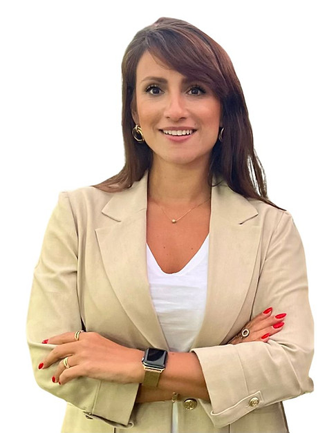 Virgínia sorri e olha para frente de braços cruzados com blazer bege e blusa branca