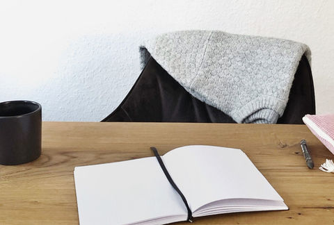 schwarzes und minimalistisches Notizbuch von pape.w mit shcwarzem Lesezeichen und 260 gepunkteten Seiten liegt offen auf einem Tisch. Daneben befindet sich eine Kaffeetasse oder Teetasse. Eine gemütliche Szene, die zum Journaling einlädt.