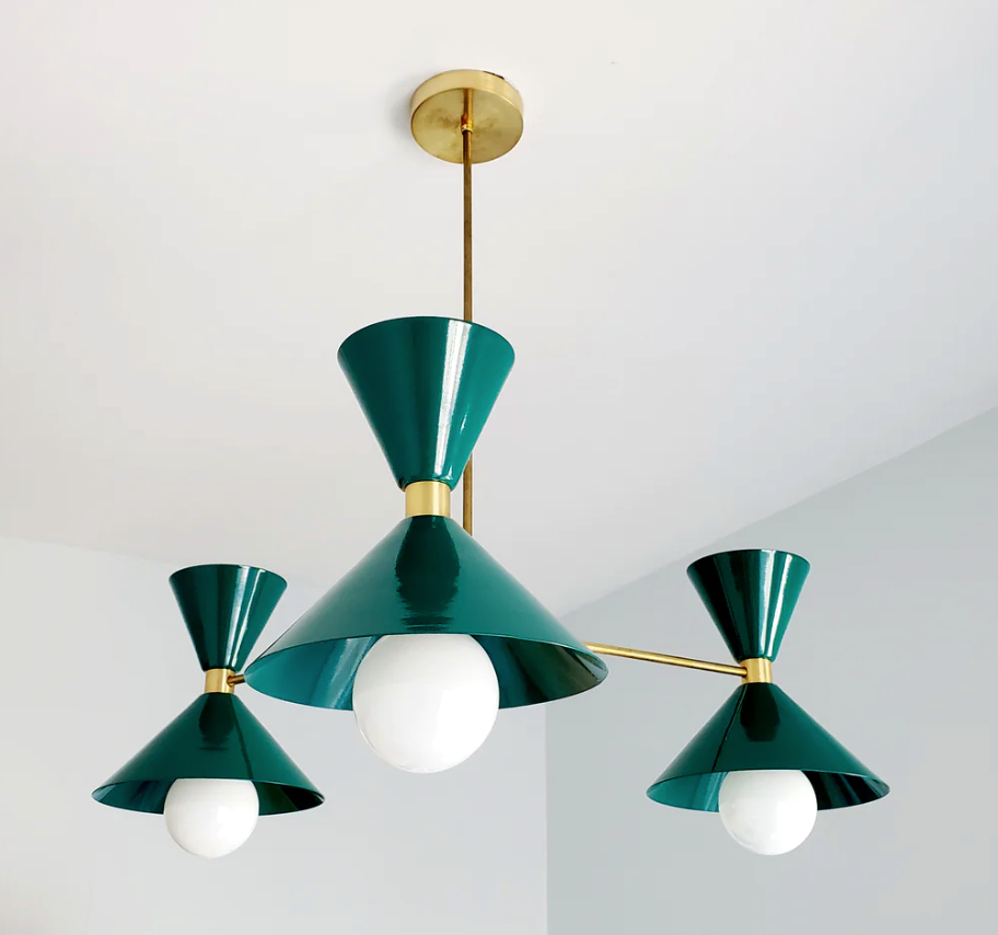 Three modern green and gold pendant lights with white bulbs hang from a ceiling in a minimalist setting, creating an elegant ambiance.