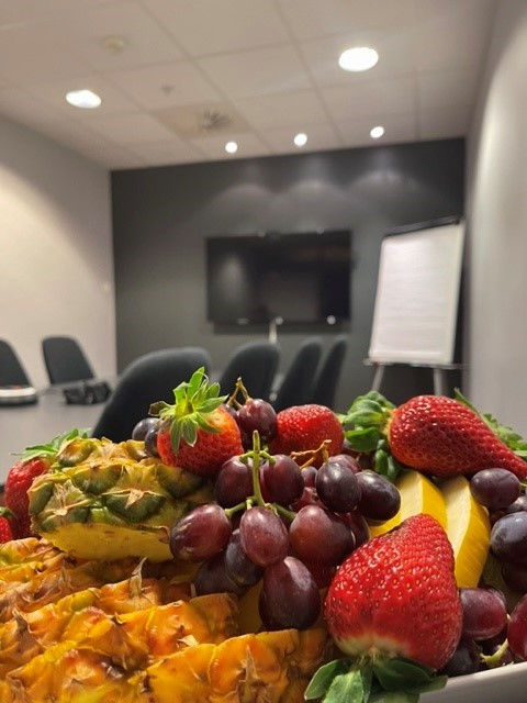 Platter of fruits with a board room in the bakground