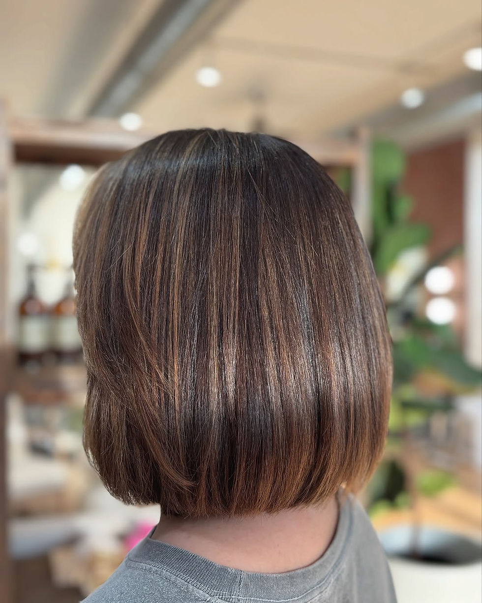 Stunning precision bob haircut with subtle brunette highlights at TRU Hair Salon , an organic hair salon in Colorado Springs. This client received a professionally executed short bob with dimensional color using our organic hair color products. Our expert stylists at TRU Hair Salon specialize in creating sleek, healthy hairstyles with eco-friendly, organic color treatments.