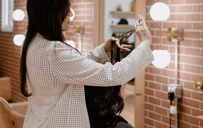 Professional stylist at TRU Hair Salon Colorado Springs creating precision layered haircut in modern salon with exposed brick